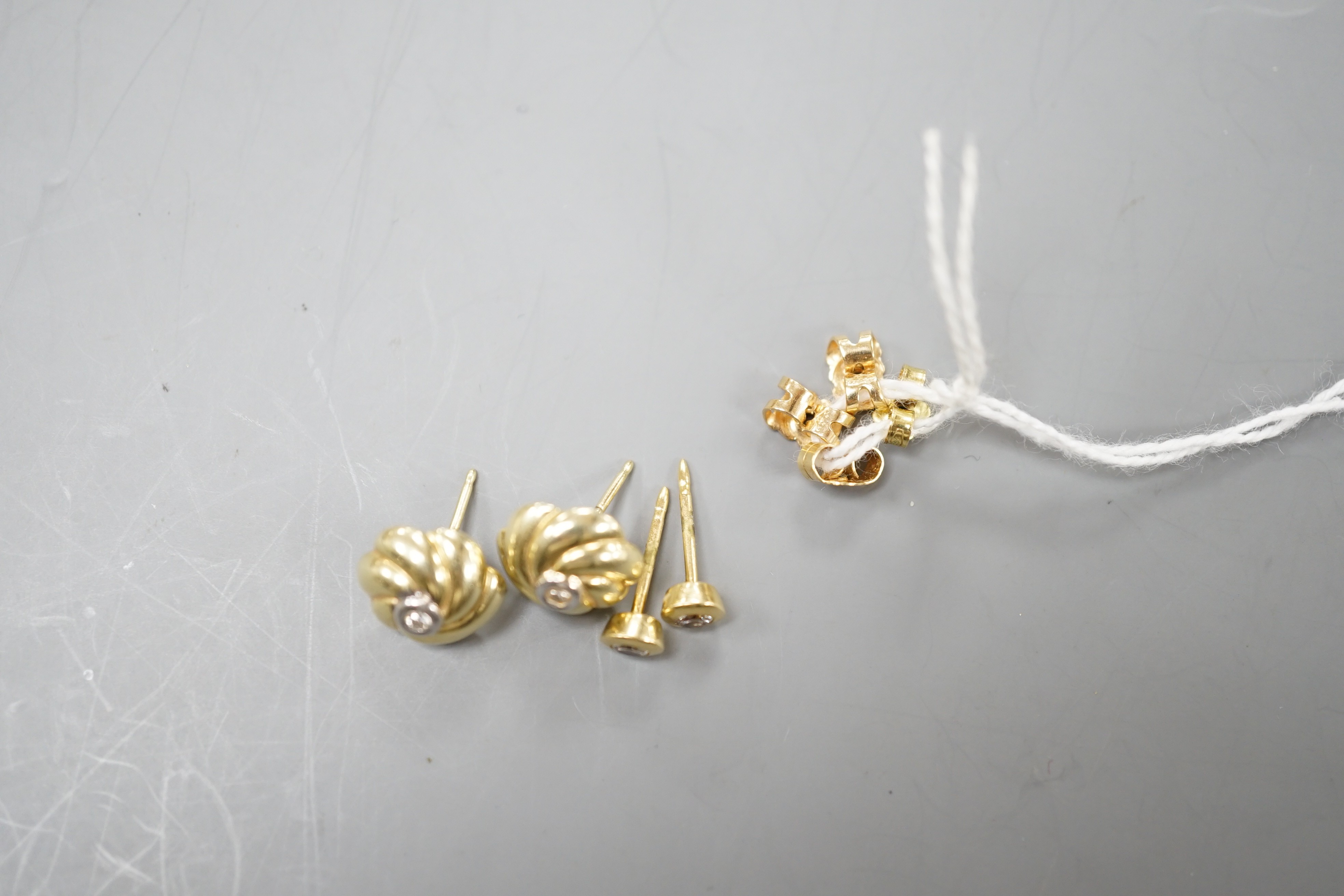 Two pairs of yellow metal and small solitaire diamond set ear studs, gross weight 5.2 grams.